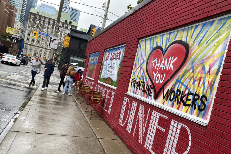 People line up to dine at a restaurant that has painted its walls to support the frontline workers in downtown Toronto, Canada, on Saturday, July 17, 2021. With nearly 70% of its adult population receiving at least one dose of a COVID-19 vaccine, Canada has the world's highest vaccination rate and is now moving on to immunize children, who are at far lower risk of coronavirus complications and death. (AP Photo/Kamran Jebreili)