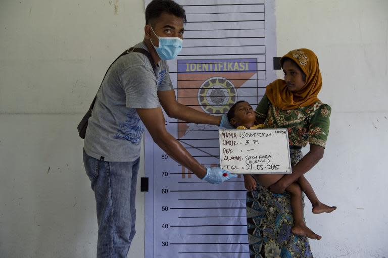 A Rohingya boy (C) from Myanmar is photographed with his mother during police identification procedures at a new confinement area in Bayeun, Aceh province on May 21, 2015 after more than 400 Rohingya migrants from Myanmar and Bangladesh were rescued