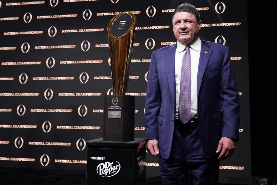 LSU head coach Ed Orgeron poses with the trophy after a news conference for the NCAA College Football Playoff national championship game Tuesday, Jan. 14, 2020, in New Orleans. LSU won 42-25 over Clemson on Monday. (AP Photo/David J. Phillip)