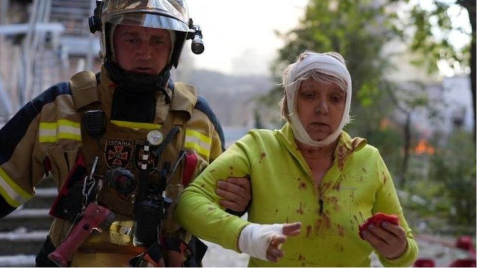 Un bombero ayuda a una mujer herida con vendas en la cabeza