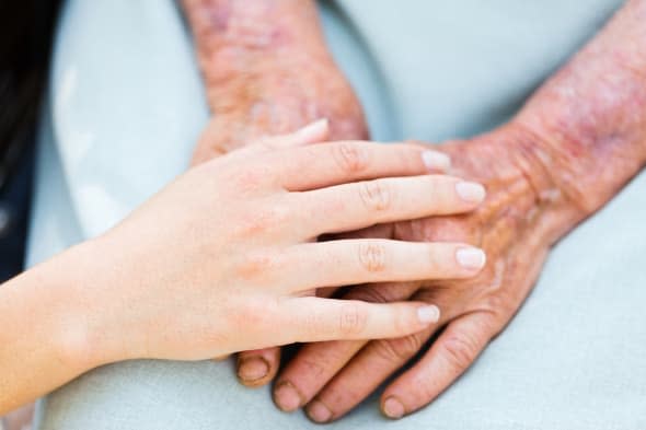 Caring woman hands over elderly hands being concept of trust and reliability.