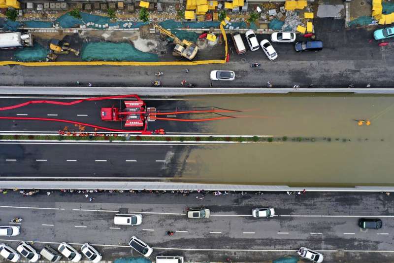 新華社7月21日發布的這張空拍照顯示，河南鄭州的消防隊員在大雨過後，正設法抽乾路面積水。（美聯社）