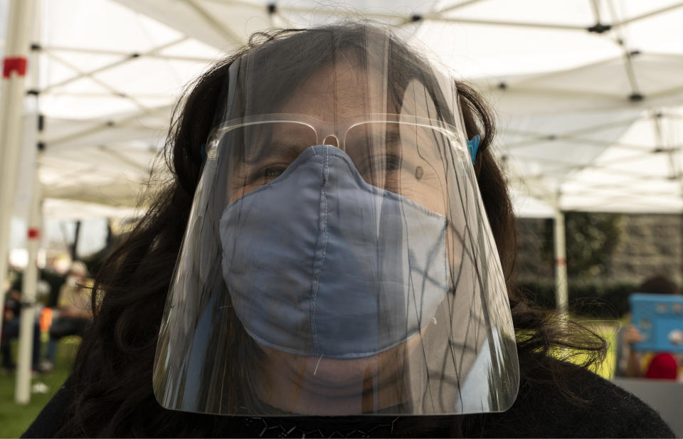 Veronica Lopez, 42, who has Spina bifida, originally from Guatemala, wears a face shield and mask protection, as she waits at the recovery tent for 15 minutes after being vaccinated at the St. John's Well Child and Family Center's COVID-19 vaccination site at the East Los Angeles Civic Center in Los Angeles, Thursday, March 4, 2021. California will begin setting aside 40% of all vaccine doses for the state's most vulnerable neighborhoods in an effort to inoculate people most at risk from the coronavirus more quickly. (AP Photo/Damian Dovarganes)