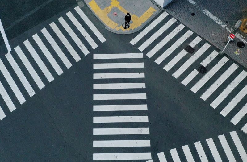 FILE PHOTO: A man waits to cross a street in front of Shinjuku station in Tokyo