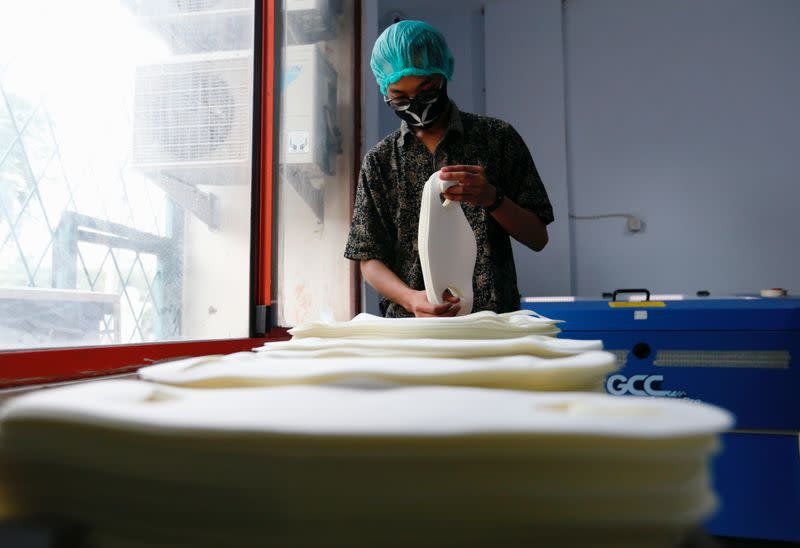 An employee wearing a protective mask and hair cap sorts face masks at the printing shop, amid the coronavirus disease (COVID-19) outbreak, in Jakarta