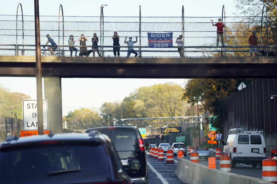 People watch the motorcade of President Donald Trump as it rolls through Arlington, Va., heading back to the White House, Saturday, Nov. 7, 2020. (AP Photo/Evan Vucci)