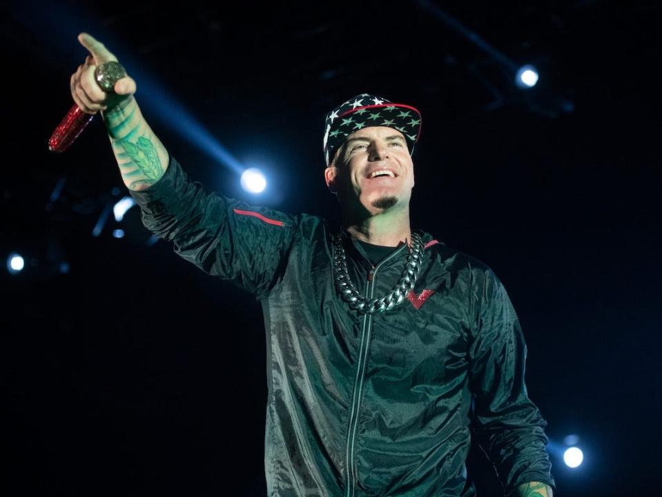 Vanilla Ice raises a microphone and smiles at a crowd during a performance.