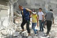 Syrians walk over rubble following air strikes on Aleppo on October 12, 2016