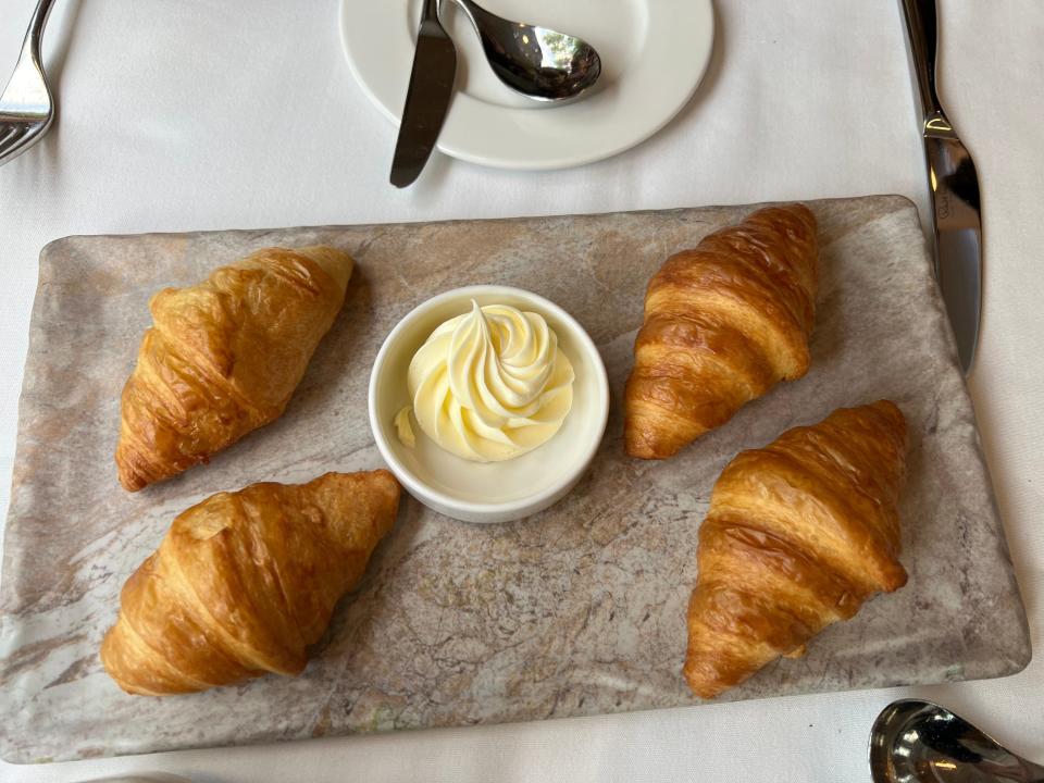 Four croissants on tray with bowl of butter in the middle