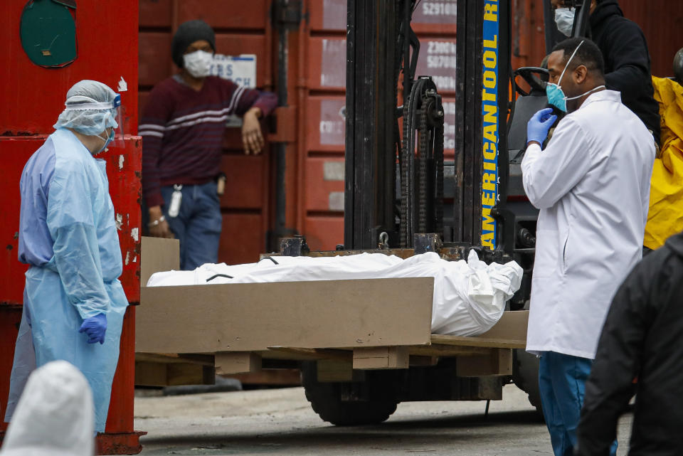 A body wrapped in plastic is prepared to be loaded onto a refrigerated container truck used as a temporary morgue by medical workers due to COVID-19 concerns, Tuesday, March 31, 2020, at Brooklyn Hospital Center in the Brooklyn borough of New York. The new coronavirus causes mild or moderate symptoms for most people, but for some, especially older adults and people with existing health problems, it can cause more severe illness or death. (AP Photo/John Minchillo)