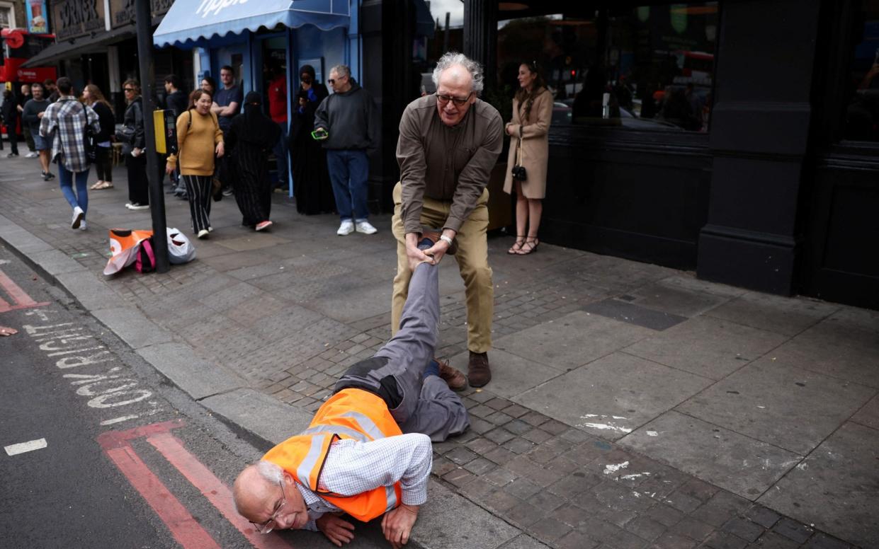 Member of the public drag activists who are blocking the road during a "Just Stop Oil" protest, in London, Britain, - REUTERS/Henry Nicholls