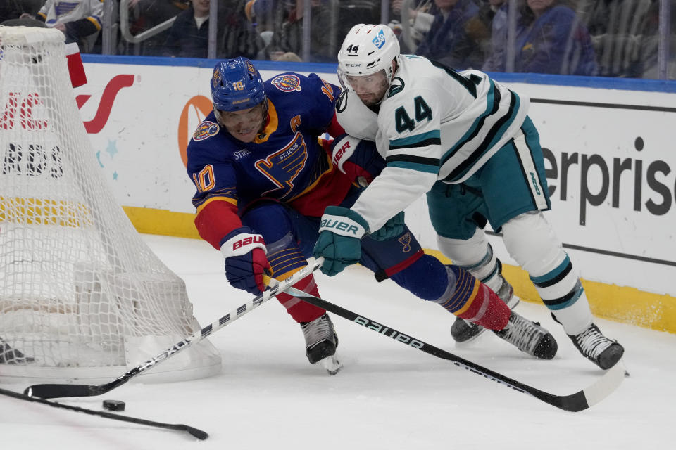 San Jose Sharks' Marc-Edouard Vlasic (44) and St. Louis Blues' Brayden Schenn (10) reach for a loose puck during the third period of an NHL hockey game Thursday, March 9, 2023, in St. Louis. (AP Photo/Jeff Roberson)