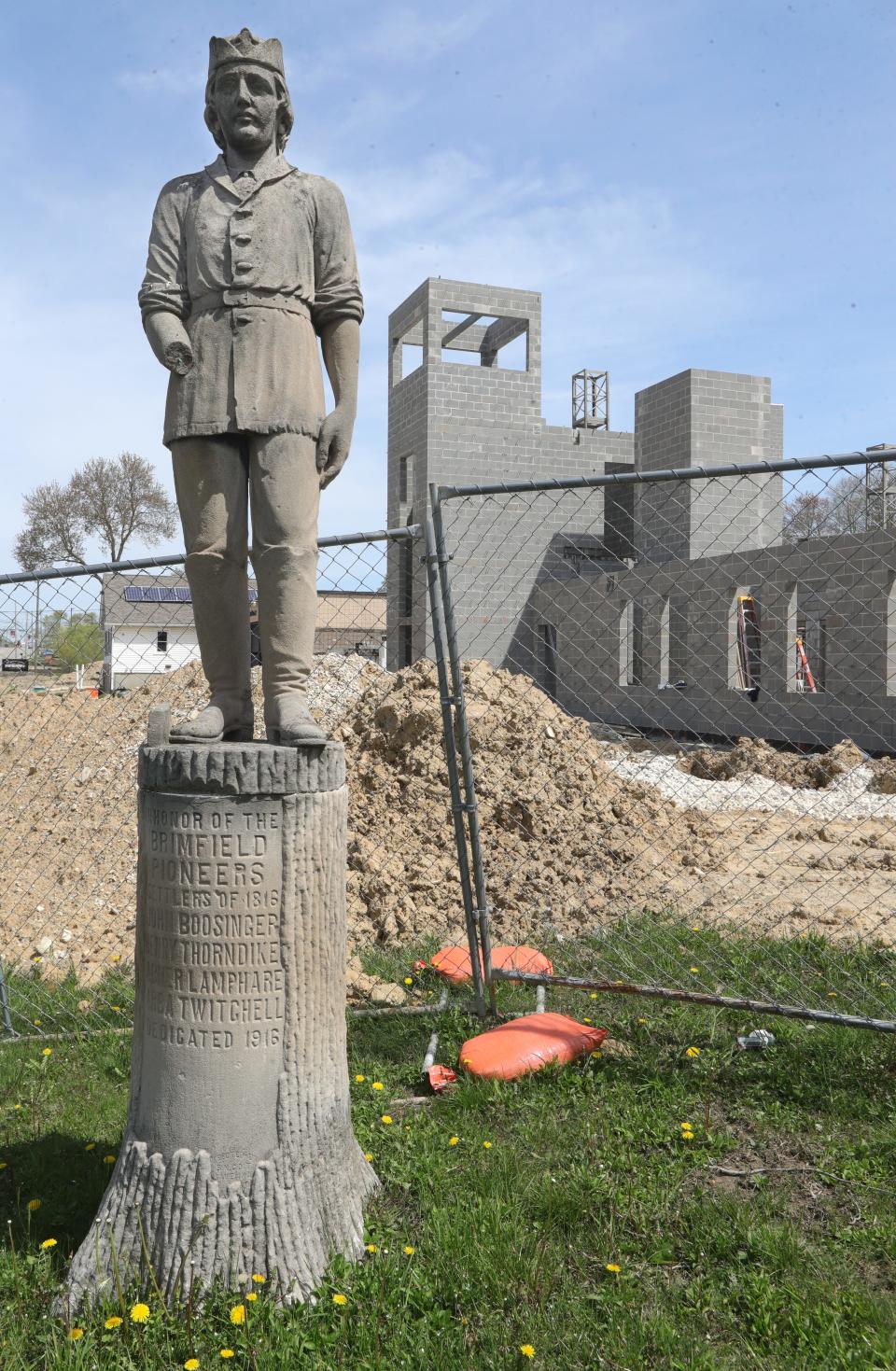 A 1916 statue honoring Brimfield pioneers stands next to a fire station under construction on Route 43 in Brimfield.