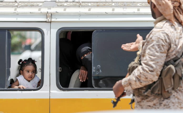 A Yemeni soldier speaks to a woman riding a bus in the port city of Mukalla on August 8, 2018. Pictured during a UAE-planned press trip