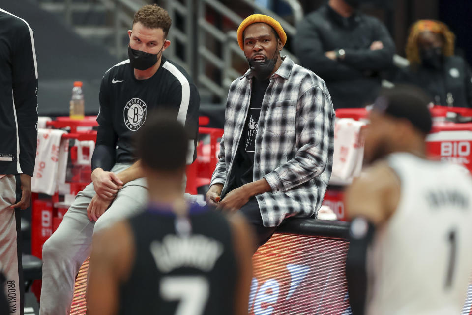 Brooklyn Nets' Kevin Durant, center, sits with Brooklyn Nets' Blake Griffin, left, during the second half of an NBA basketball game against the Toronto Raptors Wednesday, April 21, 2021, in Tampa, Fla. The Raptors won 114-103. (AP Photo/Mike Carlson)