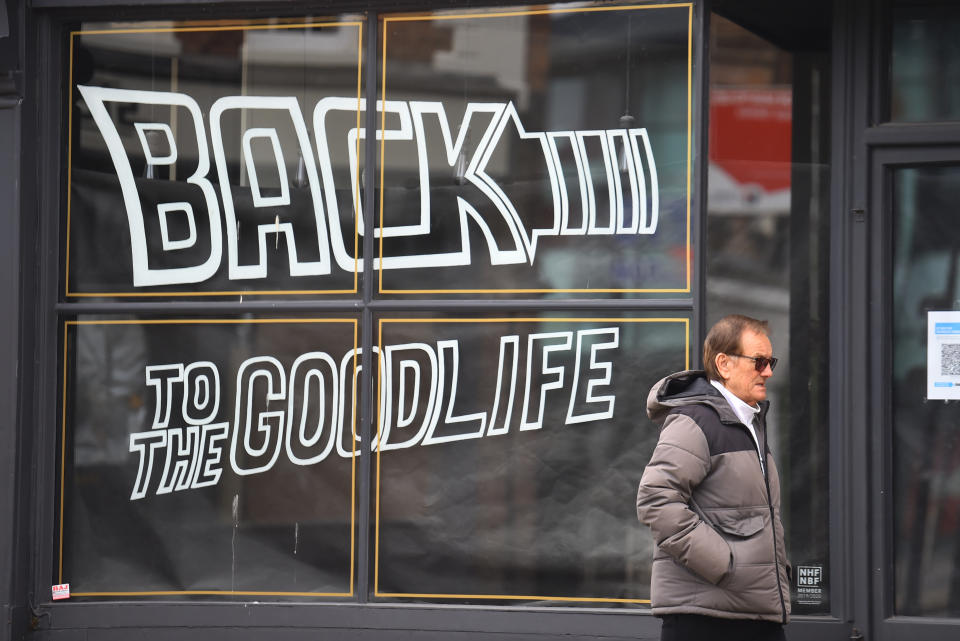 A man walks past a shop sign saying 'back to the goodlife' in Worcester town centre, England. Photo: Nathan Stirk/Getty Images