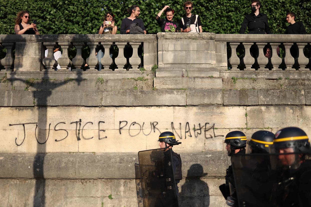 French Republican Security Corps (CRS - Compagnies Republicaines de Securite) police officers walk past a graffiti reading 