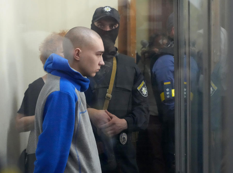 Russian army Sergeant Vadim Shishimarin, 21, is seen behind a glass during a court hearing in Kyiv, Ukraine, Friday, May 13, 2022. The trial of a Russian soldier accused of killing a Ukrainian civilian opened Friday, the first war crimes trial since Moscow's invasion of its neighbor. (AP Photo/Efrem Lukatsky)