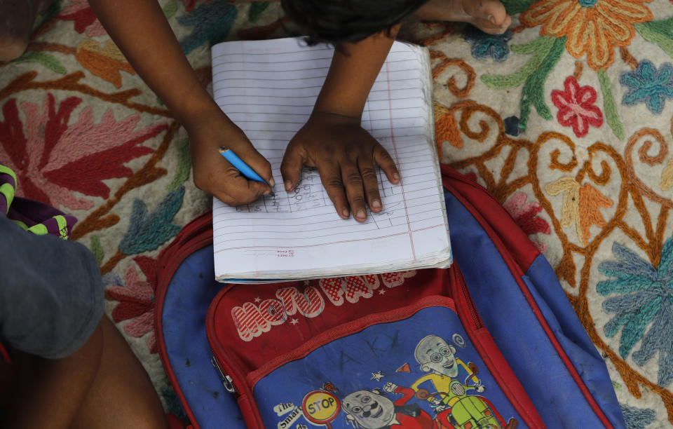 A child practices writing numbers on a sidewalk class in New Delhi, India, on Sept. 3, 2020. An Indian couple, Veena and her husband Virendra Gupta, is conducting free classes for underprivileged children on a sidewalk in New Delhi with the goal to keep them learning and not left behind when schools reopen. It all began when Veena's maid complained that with schools shut, children in her impoverished community were running amok and wasting time. As most schools in India remain shut since late March when the country imposed a nationwide lockdown to curb the spread of COVID-19, many switched to digital learning and taking classes online. (AP Photo/Manish Swarup)