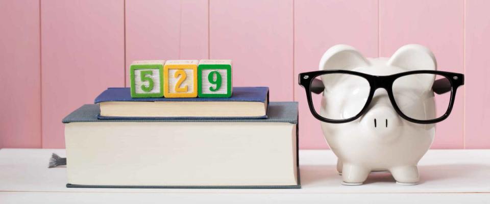 529 college savings and paying for education concept with piggy bank wearing eyeglasses alongside textbooks