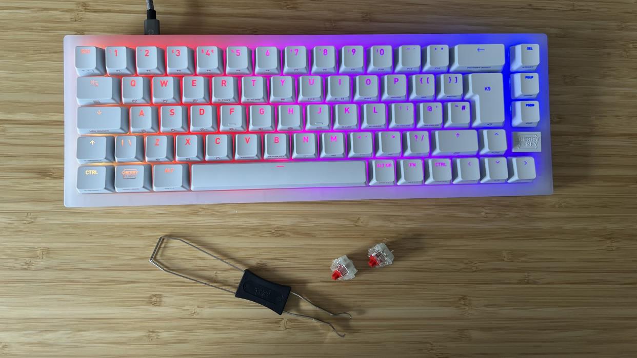  Cherry XTRFY K5V2 gaming keyboard on a wooden desk with switches and swapping tool below. 