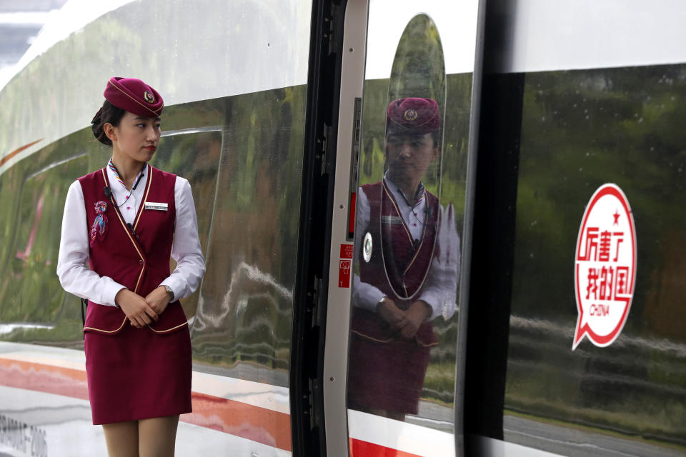 In this Monday, Oct. 16, 2017, photo, an attendee waits for passengers to board the Fuxing, China's latest high speed train with a sticker reads "Incredible, my country" parked at Hongqiao Railway Station in Shanghai, China. A spokesman for China's ruling Communist Party on Tuesday promised Beijing will open its markets further and tried to reassure foreign companies amid mounting U.S. and European trade complaints. (AP Photo/Andy Wong)