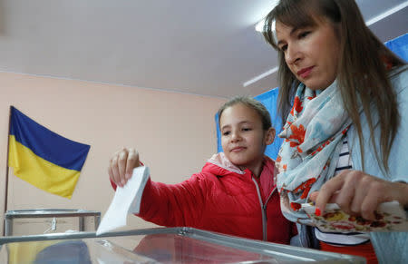 People stand in front of a ballot box while casting a vote a polling station during the second round of a presidential election in Kiev, Ukraine April 21, 2019. REUTERS/Valentyn Ogirenko