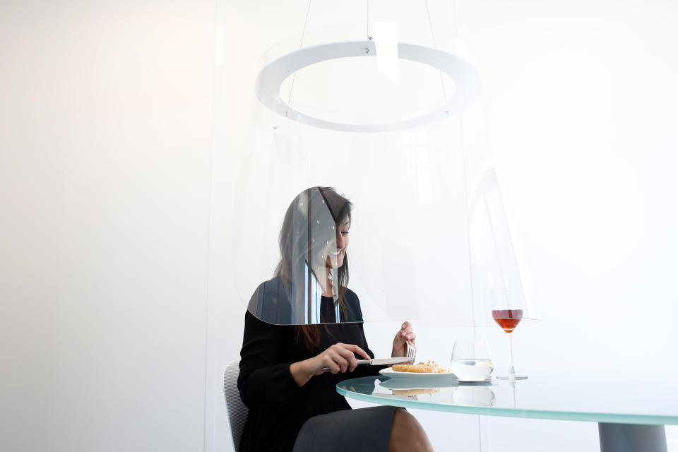 A woman poses under a Plex'Eat prototype plexiglas bubble by designer Christophe Gernigon which surrounds diners to protect them from the novel coronavirus during a presentation in Cormeilles-en-Parisis, near Paris, as restaurants in France prepare to re-open post-lockdown, May 20, 2020. Picture taken May 20, 2020.  REUTERS/Benoit Tessier