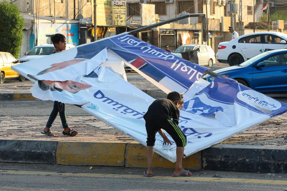 Demonstrators tear down electoral posters for the early parliamentary elections during anti-government protests in Najaf, Iraq, Friday, Oct. 1, 2021. The candidates know convincing Iraq's disillusioned youth to trust in an electoral process tainted with a history of tampering and fraud is their best chance to win seats. (AP Photo/Anmar Khalil)