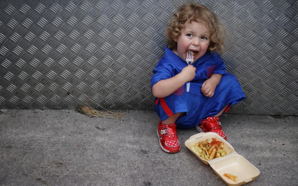 Soccer Football - Women's Euro 2022 - Group A - England v Austria - Old Trafford, Manchester, Britain - July 6, 2022 A young England fan eats food outside the stadium before the match - Molly Darlington/Reuters