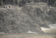 Villagers look at the broken bridge destroyed by the lava flow following the eruption of Mount Semeru in Lumajang district, East Java province, Indonesia, Sunday, Dec. 5, 2021. The death toll from the eruption of the highest volcano on Indonesia's most populous island of Java has risen by a score of still missing, officials said Sunday as rain continued to lash the area and hamper the search. (AP Photo/Hendra Permana)