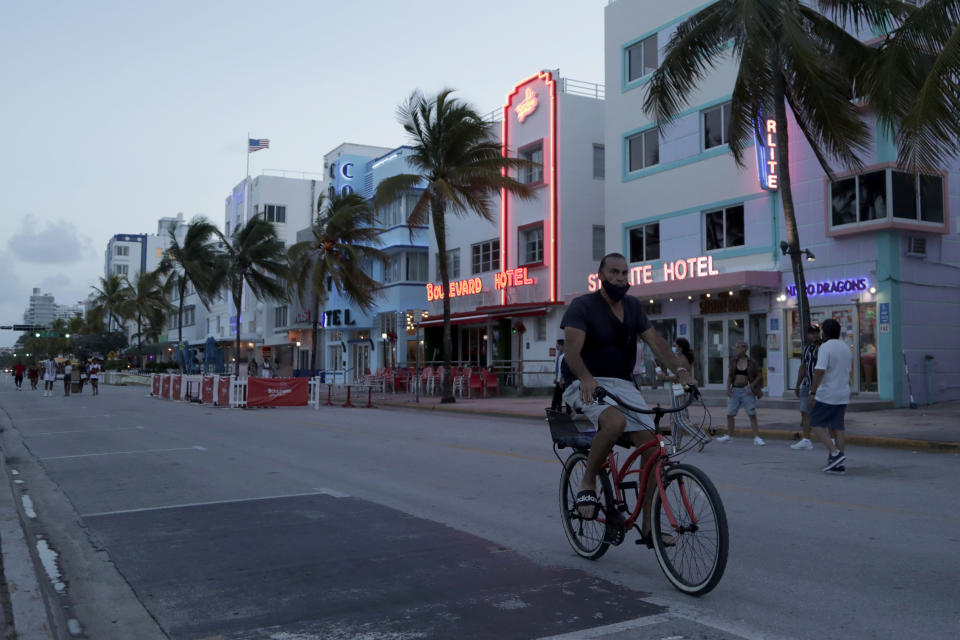 FILE - In this July 24, 2020, file photo, a sparse crowd is on Ocean Drive after an 8 p.m. curfew amid the coronavirus pandemic in Miami Beach, Fla. Families trying to get in a last-minute vacation before school starts better do some homework on COVID-19 restrictions before loading up the minivan. (AP Photo/Lynne Sladky, File)