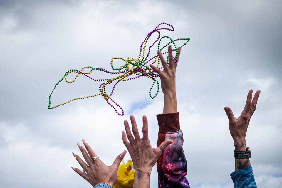 A crowd lining the beach grabs for beads thrown from a parade float during the Barefoot Mardi Gras Parade on North Padre Island, Feb. 18, 2023, in Corpus Christi, Texas.