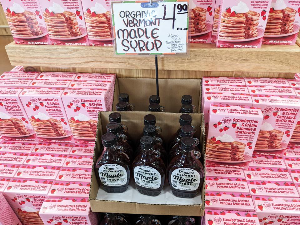 Bottles of organic Vermont maple syrup surrounded by boxes of strawberries and crème pancake and waffle mix at Trader Joe's.