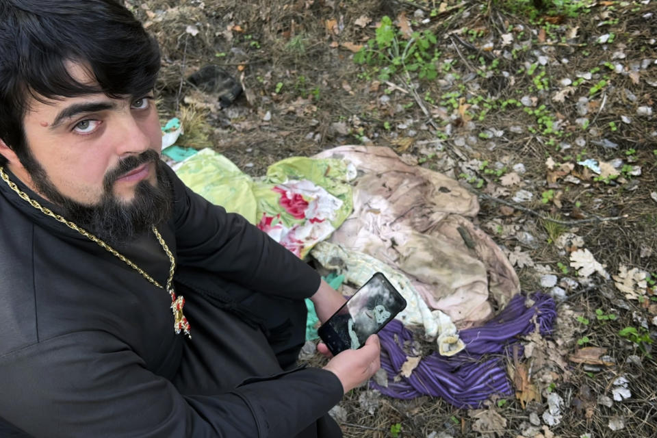 Father Vasyl Bentsa matches photos he made when he discovered the bodies of five men tortured and shot by Russian troops in Zdvyzhivka, Ukraine, including Mykola "Kolia" Moroz, 47, with potential evidence of the crime left in the forest where the men were buried. (AP Photo/Erika Kinetz)