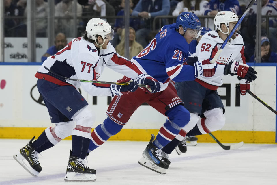 New York Rangers' Jimmy Vesey, center, races for the puck with Washington Capitals' T.J. Oshie, left, and Dylan McIlrath during the first period in Game 1 of an NHL hockey Stanley Cup first-round playoff series, Sunday, April 21, 2024, in New York. (AP Photo/Seth Wenig)