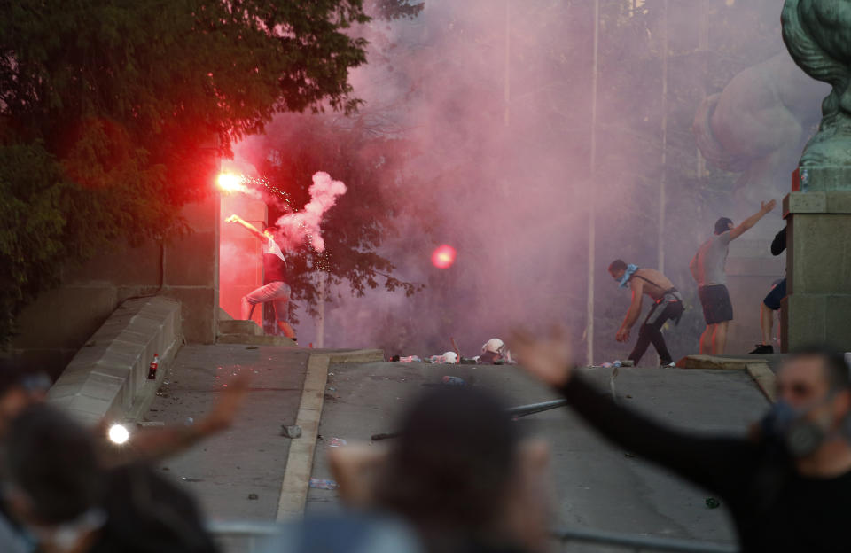 Protesters clash with Serbian riot police in Belgrade, Serbia, Wednesday, July 8, 2020. Police have fired tear gas at protesters in Serbia's capital during the second day of demonstrations against the president's handling of the country's coronavirus outbreak. President Aleksandar Vucic backtracked on his plans to reinstate a coronavirus lockdown in Belgrade this week, but it didn't stop people from firing flares and throwing stones while trying to storm the downtown parliament building. (AP Photo/Darko Vojinovic)