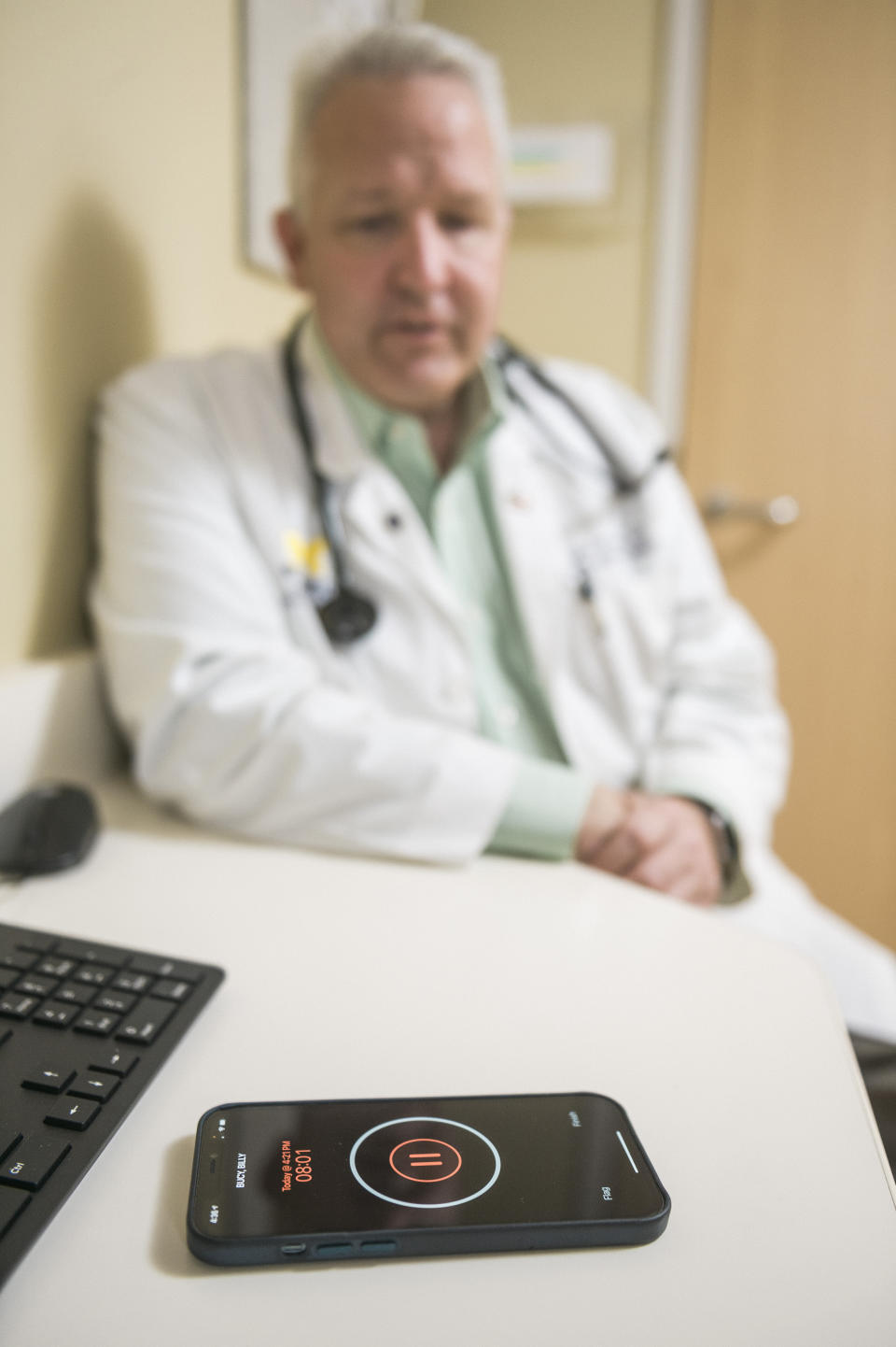 In this photo provided by University of Michigan Health-West, Dr. Lance Owens, chief medical information officer at the university, demonstrates the use of an AI tool on a smartphone in Wyoming, Mich., on Sept. 9, 2021. The software listens to a doctor-patient conversation, documents and organizes it to write a clinical note. (University of Michigan Health-West via AP)