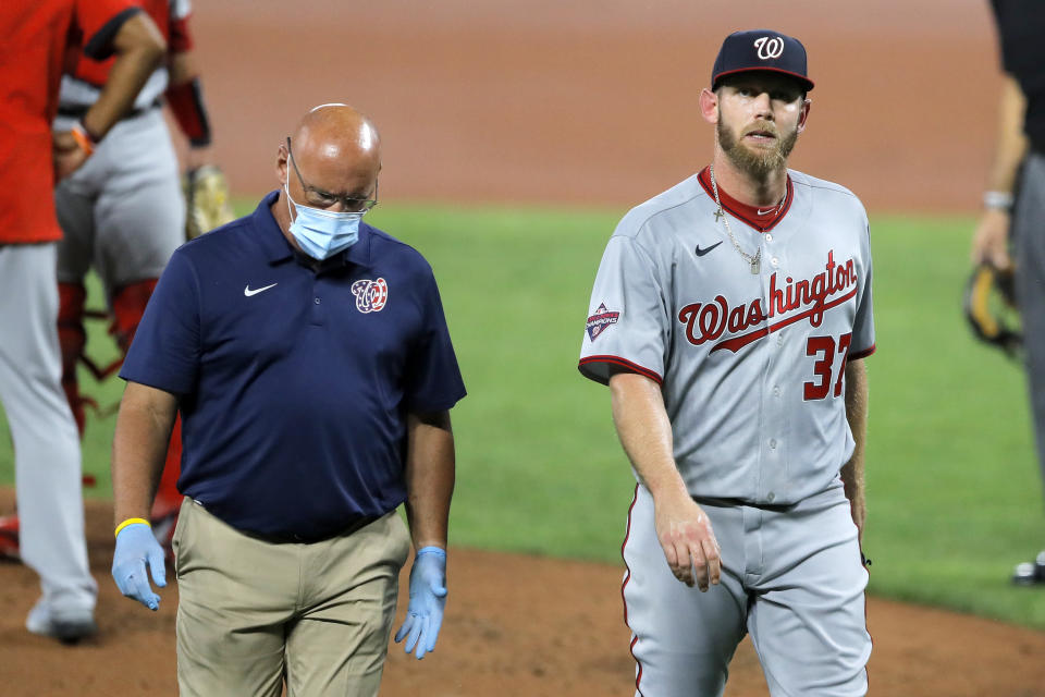 Washington Nationals starting pitcher Stephen Strasburg, right, walks with a member of the training staff as he heads to the dugout after leaving the game during the first inning of a baseball game against the Baltimore Orioles, Friday, Aug. 14, 2020, in Baltimore. (AP Photo/Julio Cortez)