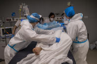 A medical team of the new Nurse Isabel Zendal Hospital rotates a patient at the COVID-19 ICU ward in Madrid, Spain, Monday, Jan. 18, 2021. As the coronavirus curve of contagion turned increasingly vertical after Christmas and New Year's, the Zendal has been busy. On Monday, 392 virus patients were being treated, more than in any other hospital in the Madrid region. (AP Photo/Bernat Armangue)