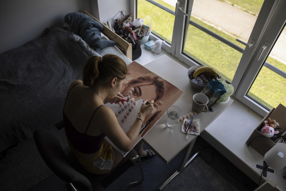 Valentyna, a Ukrainian refugee from the Lviv area, works on a self-portrait in a room at a refugee shelter in Warsaw, Poland, Wednesday, Aug. 17, 2022. As Russia’s war against Ukraine reaches the sixth-month mark, many refugees are coming to the bitter realization that they will not be returning home soon. With shelling around a nuclear power plant and missiles threatening even western regions of Ukraine, many refugees don’t feel safe at home, even if those areas are under Ukrainian control. (AP Photo/Michal Dyjuk)