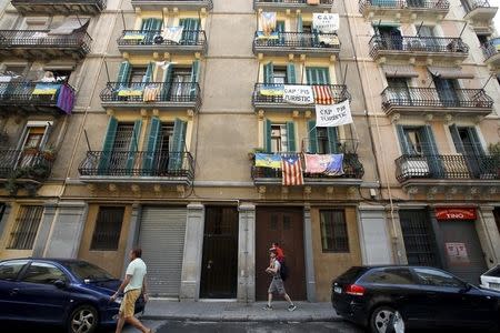 Banners against touristic apartments hang from balconies as people walk past them at Barceloneta neighborhood in Barcelona, Spain, August 18, 2015. REUTERS/Albert Gea