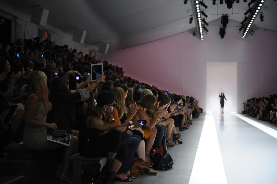 Camera phones and ipads are illuminated as designer Jill Stuart waves to the audience after her Spring 2013 collection was modeled during Fashion Week in New York, Saturday Sept 8, 2012. (AP Photo/Stephen Chernin)