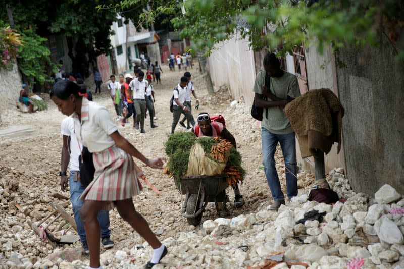 Residents walk along a street affected by the passage of Tropical Storm Laura, in Port-au-Prince