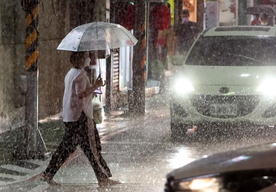 軒嵐諾颱風2日持續接近台灣東北部，直至晚間為台灣北部帶來間歇性的風雨，民眾撐傘穿越馬路。（鄭任南攝）
