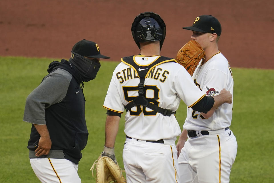 Pittsburgh Pirates pitching coach Oscar Marin, left, talks with starting pitcher Mitch Keller, right, and catcher Jacob Stallings after the Cincinnati Reds scored three runs in the fourth inning of a baseball game, Monday, May 10, 2021, in Pittsburgh. (AP Photo/Keith Srakocic)