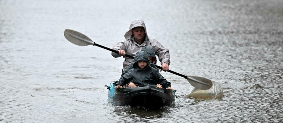 Des gens font du kayak le long d'une rue inondée, depuis le débordement de la rivière Hawkesbury, en raison de pluies torrentielles dans la banlieue de Windsor à Sydney le 4 juillet 2022. 
 
