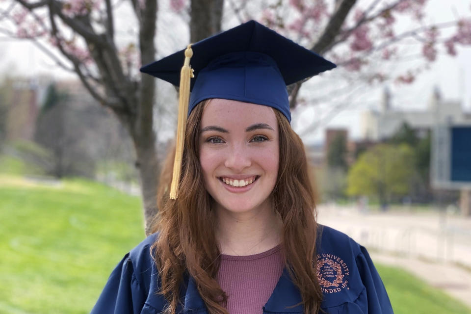 In this photo provided by Bailie Brown, Bailie Brown poses in the cap and gown she'll wear at graduation in Syracuse, N.Y., in this April 2021 photo. Brown doesn't consider herself a trailblazer, and yet in a way she is — and so is her school. In late May she'll become the first woman to graduate from Syracuse University's Falk College with a Bachelor of Science degree in sport analytics. (Bailie Brown via AP)
