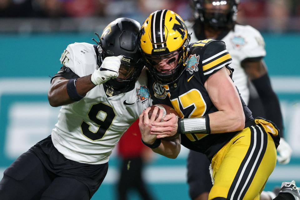 Missouri Tigers quarterback Brady Cook (12) runs into Wake Forest Demon Deacons defensive back Chelen Garnes (9) in the second quarter in the 2022 Gasparilla Bowl at Raymond James Stadium.