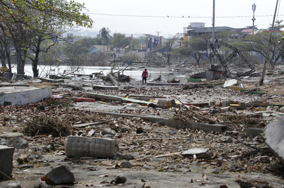 A man walks past the remains of structures at a park after it was destroyed in the massive earthquake and tsunami that hit Palu, Central Sulawesi, Indonesia Thursday, Oct. 4, 2018. Life is on hold for thousands living in tents and shelters in the Indonesian city hit by a powerful earthquake and tsunami, unsure when they'll be able to rebuild and spending hours each day often futilely trying to secure necessities such as fuel for generators. (AP Photo/Aaron Favila)